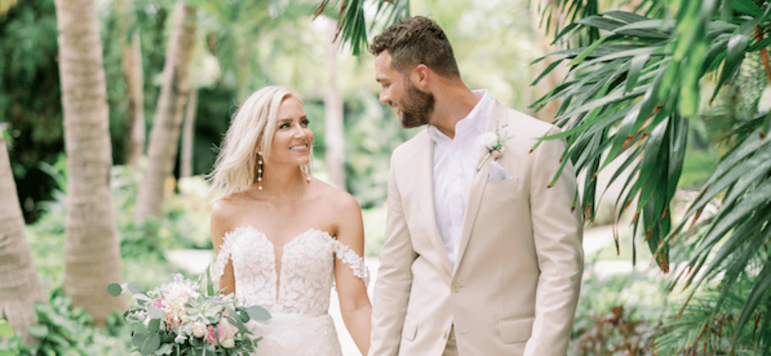 A couple just married walking through a garden with tropical trees in the background