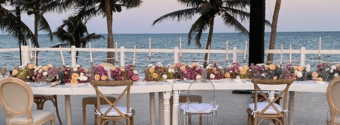 Hyatt Zilara Riviera Maya terrace set up with a long white table with purple flowers and candle sticks on it looking out at the beach