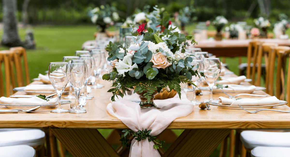 March Header Close up of the arrangements on a table at a destination wedding with blush table settings and green florals