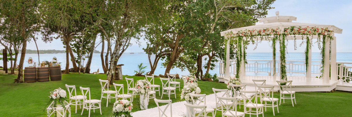View of a destination wedding set up at a gazebo with trees around and the ocean in the background