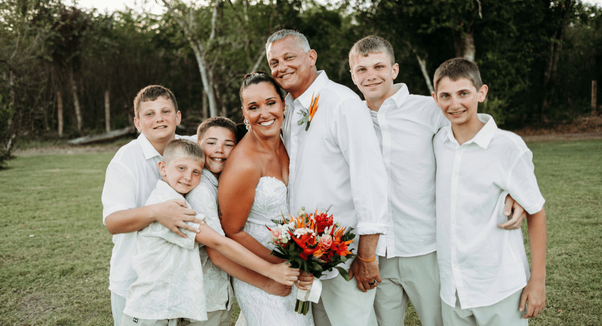 Bride and groom smiling for a portrait with their five boys at a destination wedding