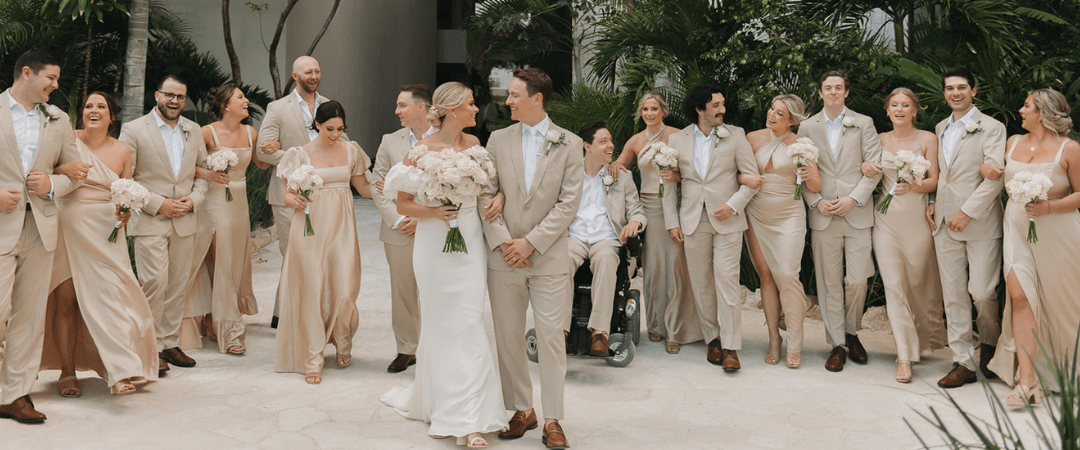 Destination wedding party standing in a line behind the bride and groom, all smiling and walking