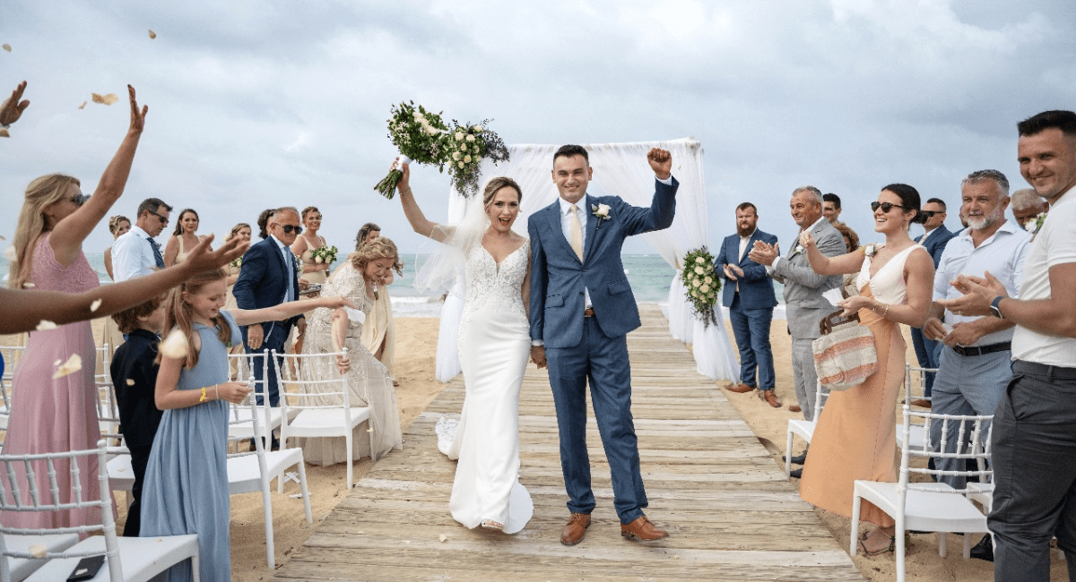 When Should Guests Book Travel for a Destination Wedding Bride and groom walking down aisle after wedding ceremony