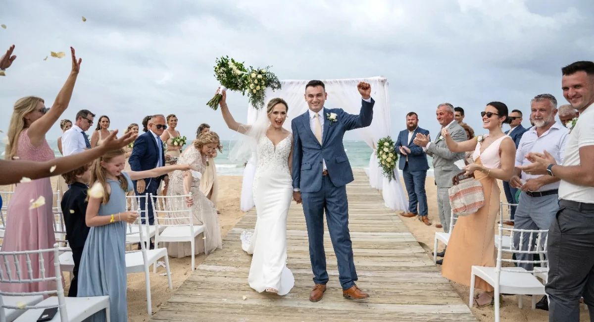 When Should Guests Book Travel for a Destination Wedding Bride and groom walking down aisle after wedding ceremony