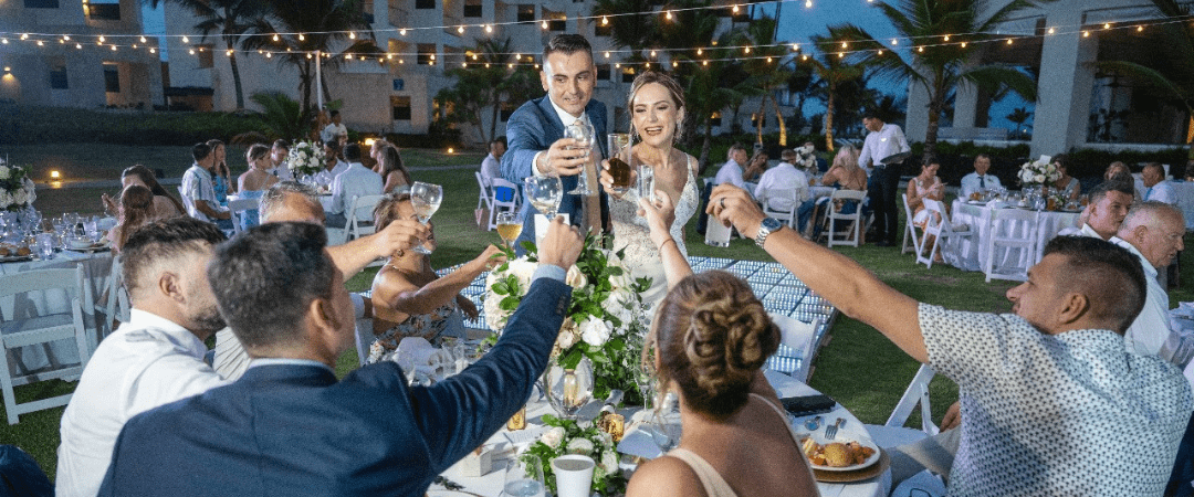 Bride and groom toasting with their wedding guests who booked their travel in advance for the destination wedding