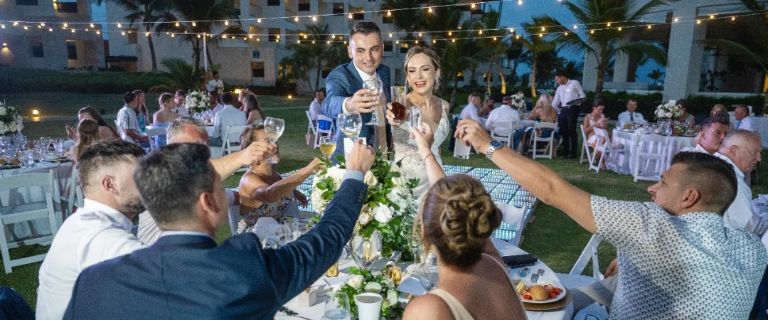 Bride and groom toasting with their wedding guests who booked their travel in advance for the destination wedding