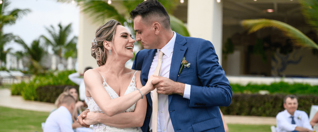 Bride and groom hand in hand smiling at each other during the reception with all their guests that traveled for their destination wedding
