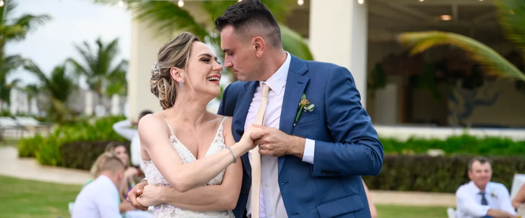 Bride and groom hand in hand smiling at each other during the reception with all their guests that traveled for their destination wedding